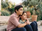 נער ואח צעיר יושבים על מדרגות אבן