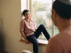 נער יושב על אדן חלון וצוחק